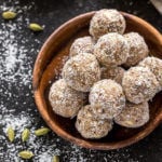 overhead shot of coconut cardamom energy bites with green cardamom pods on the side