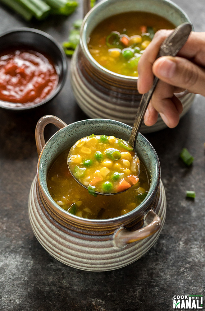 sweet corn soup in a ladle with another bowl of soup in the background