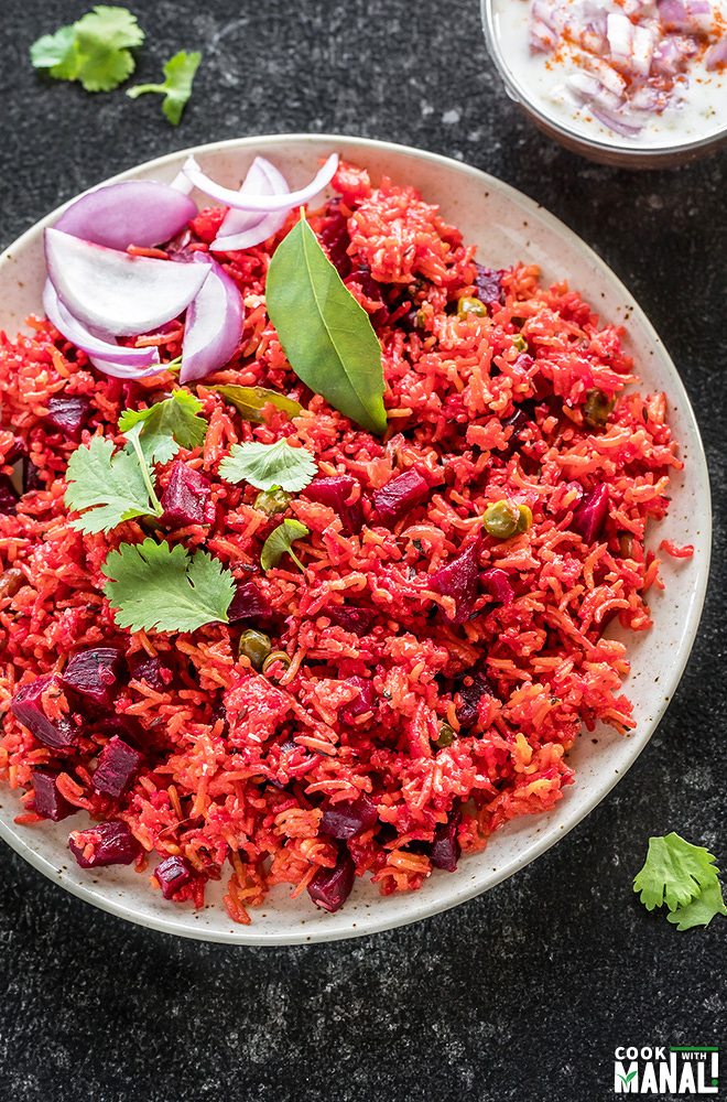 beetroot pulao in a plate served with yogurt and sliced onions