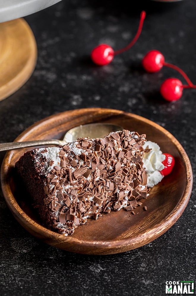 slice of eggless black forest cake in a wooden plate