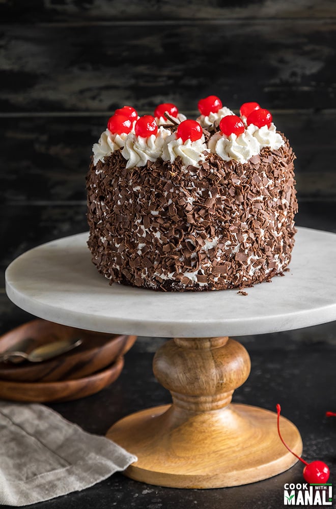 eggless black forest cake on a white marble cake stand