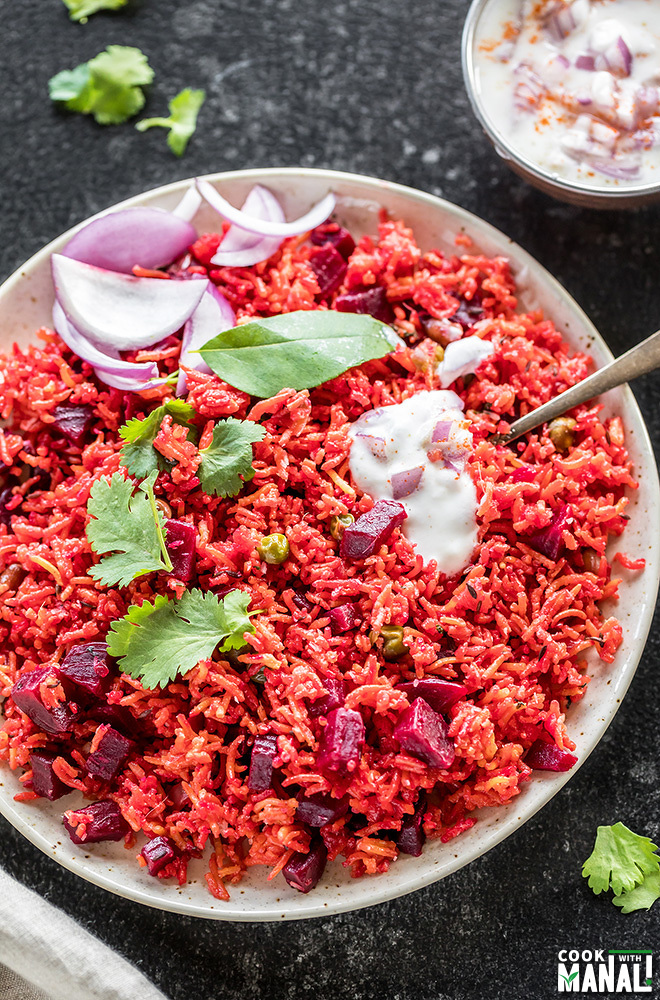 beetroot pulao in a white plate garnished with cilantro and a dollop of yogurt on top