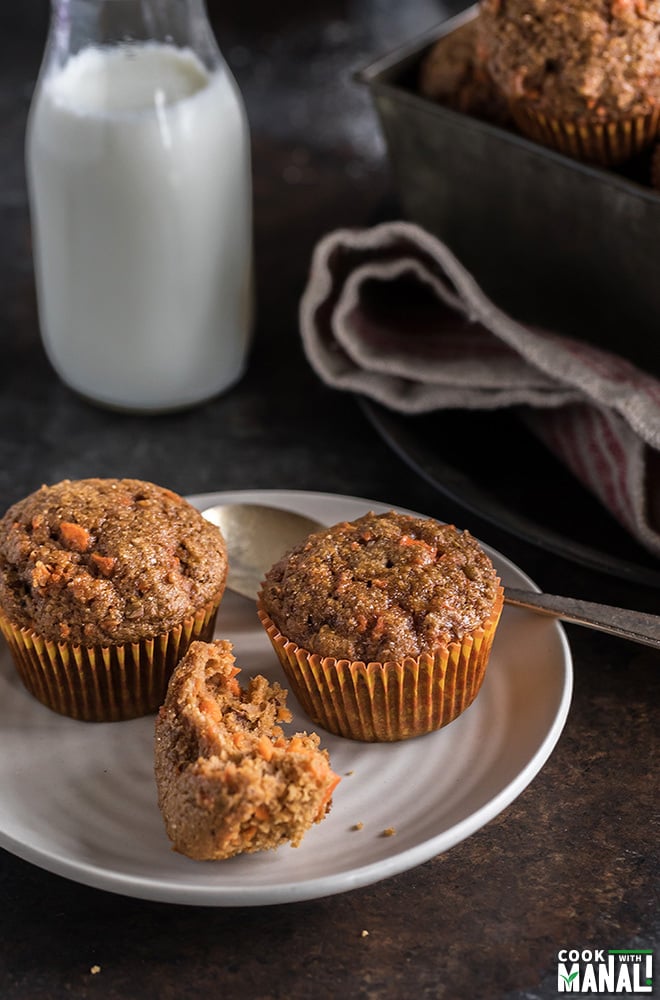 2 carrot muffins in a white plate with one half eaten muffin