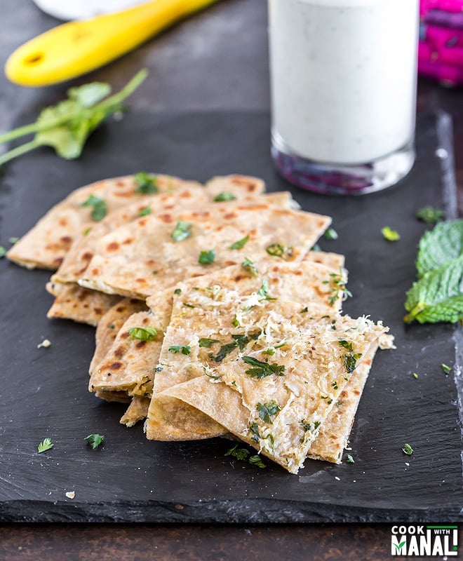 cut pieces of mooli paratha on a black tray with the front piece of paratha cut open to show the filling