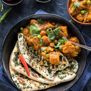 vegetable korma served along with naan in a black bowl