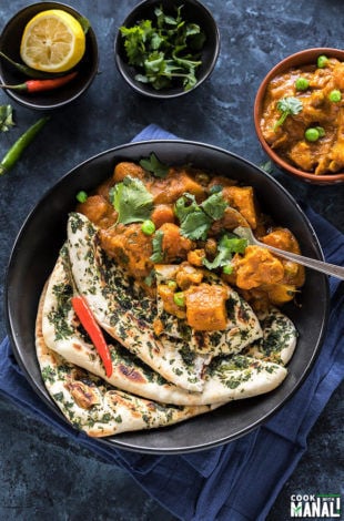 vegetable korma served along with naan in a black bowl