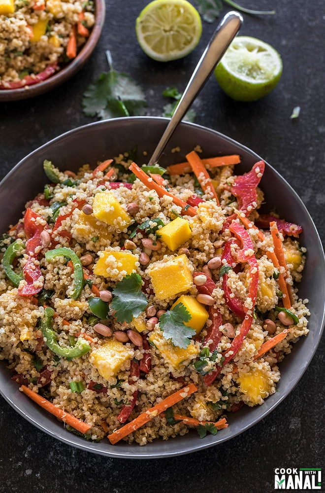 quinoa mango salad in a grey bowl with a spoon on the side