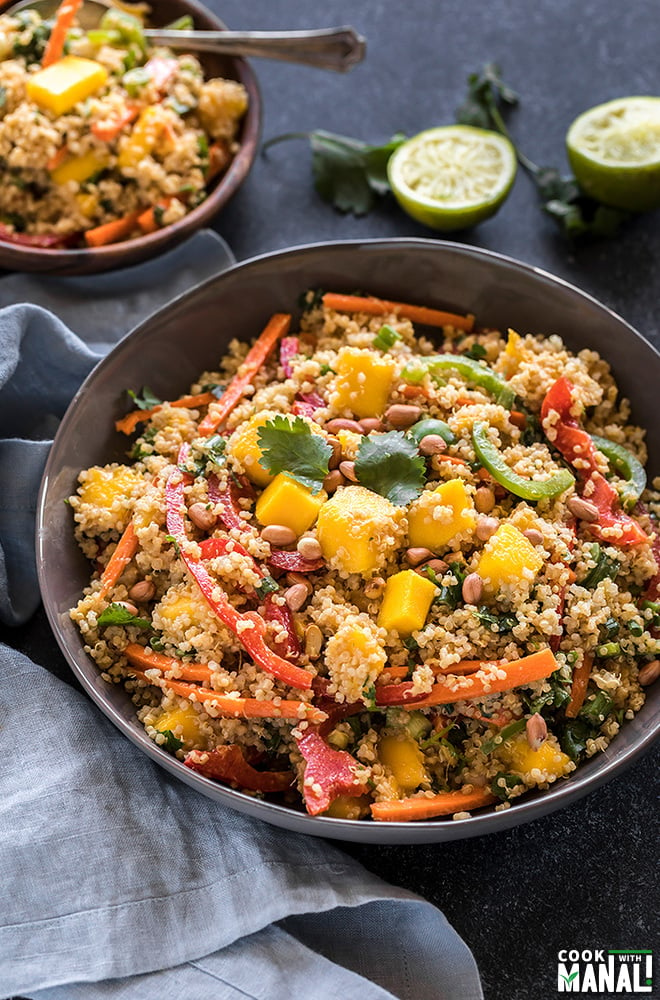 quinoa mango salad in a large grey bowl with a blue napkin on the side and some lime and cilantro in the background