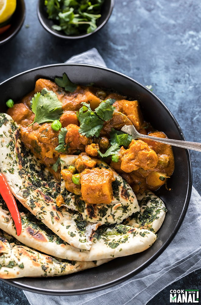 vegetable korma with naan and garnished with cilantro and red chili