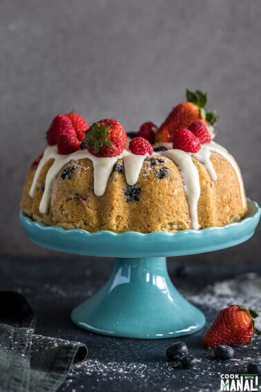 instant pot berry vanilla cake topped with fresh berries and placed on a blue cake stand
