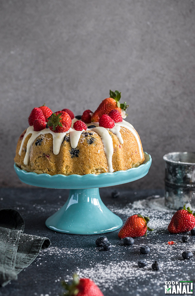 instant pot berry vanilla cake topped with fresh berries and placed on a blue cake stand