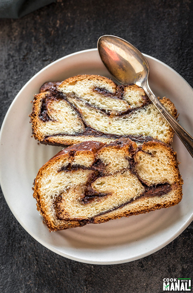 two slices of nutella babka in a small white plate along with a spoon