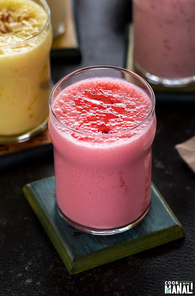 glass of rose lassi on a coaster with more glasses of lassi in the background