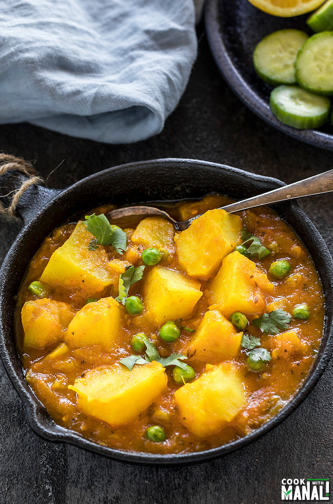 instant pot aloo matar served in a small black skillet with a spoon on the side