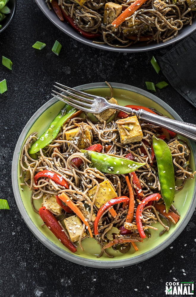 vegan soba noodles in a round yellow plate with a fork