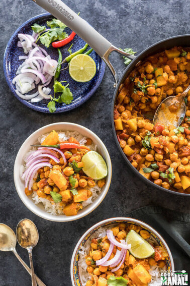 chana aloo served in 2 white bowls and topped with sliced onion and lime wedge