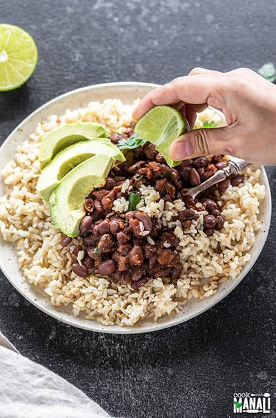 instant pot beans and brown rice served in a white place with sliced avocados