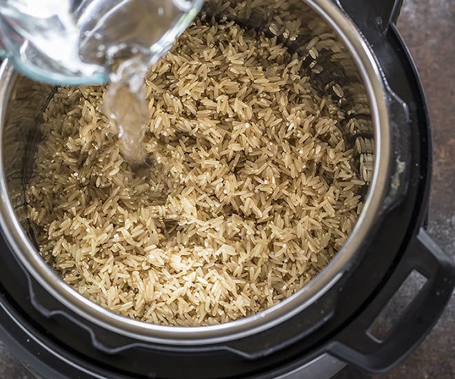 water being added to brown rice in an instant pot