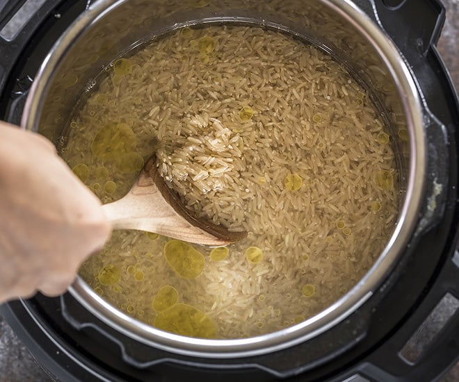 brown rice being stirred in the instant pot