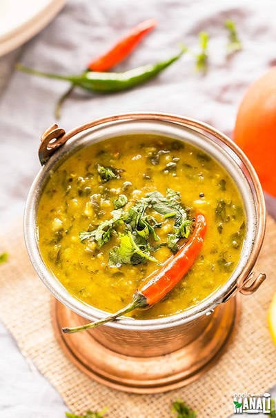 spinach dal served in a copper container and garnished with cilantro