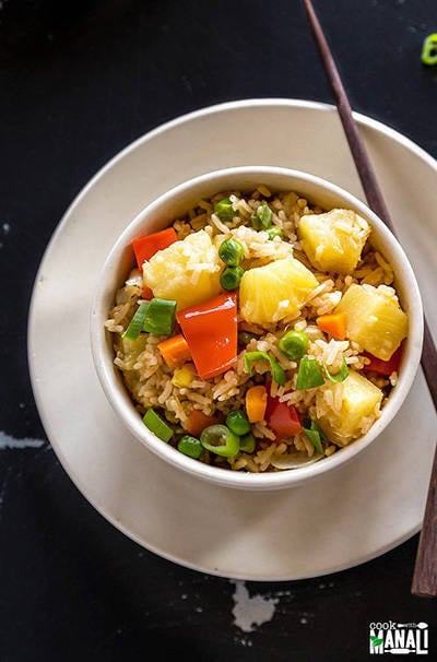 vegan pineapple fried rice in a white bowl with a pair of chopsticks on the side