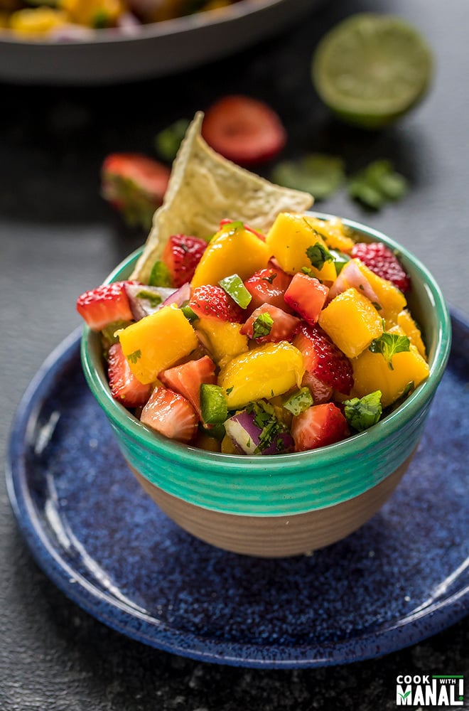 mango salsa in a blue bowl served with chips on the side