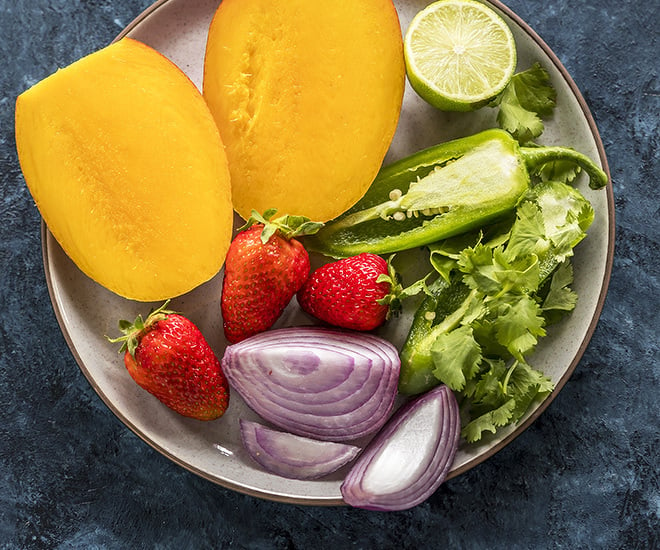 cut mangoes, strawberries, cut onion, cut lime and slice jalapeno in a plate