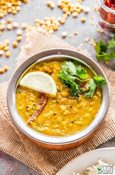 chana dal served in a round copper vessel garnish with cilantro