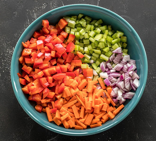 a blue bowl with chopped peppers, onion, carrots and celery