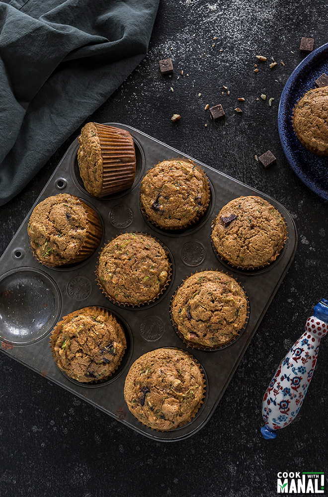 healthy zucchini muffins in a muffin tray with a whisk on the side