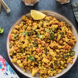 tofu scramble in a round plate with a glass of chai in the background
