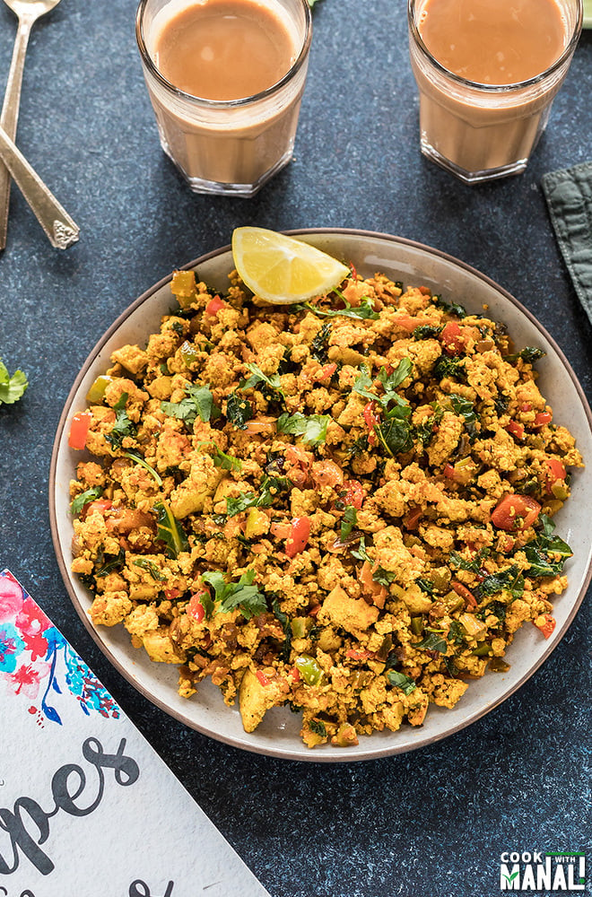 tofu scramble in a round plate with a glass of chai in the background