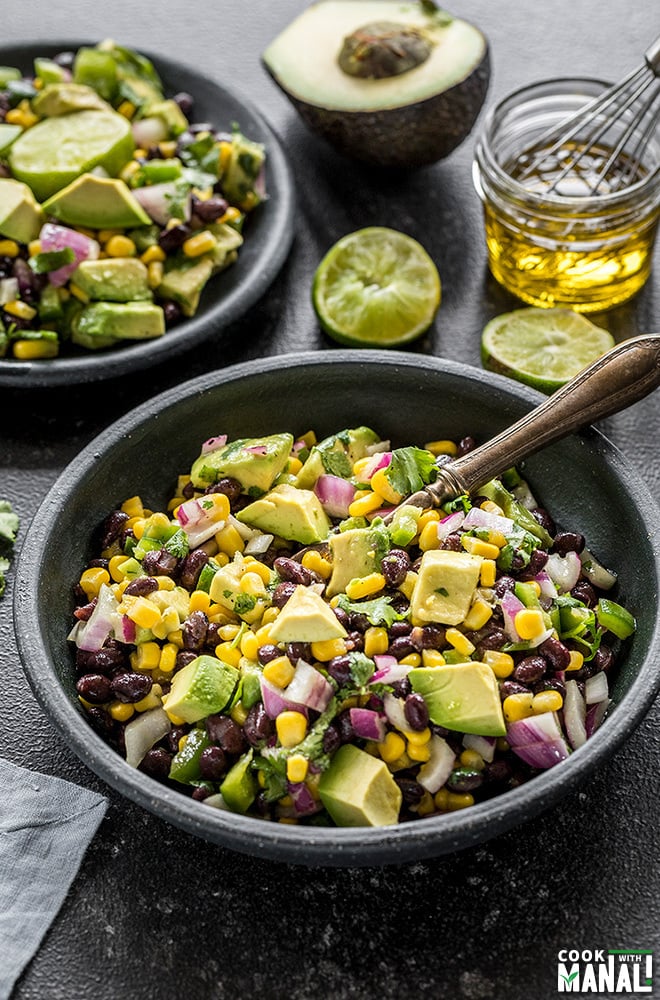 black bean and corn salad served in a small black bowl with a spoon