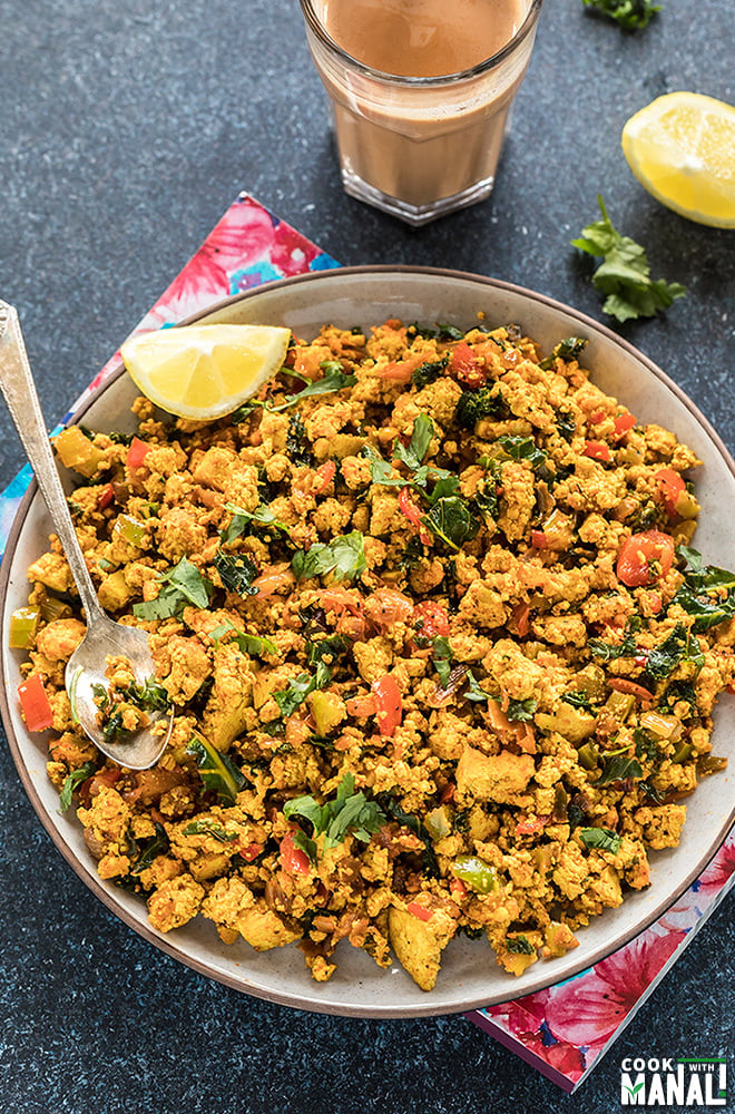 tofu scramble in a round plate with a glass of chai in the background