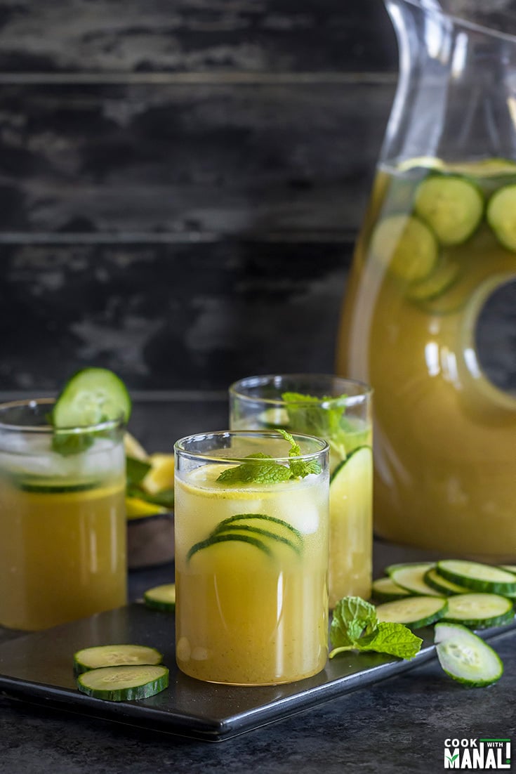 3 glasses of cucumber lemonade with a pitcher in the background