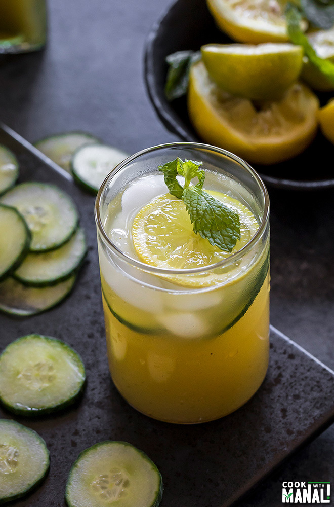 a glass of cucumber lemonade with cucumber slices, lemon slice and mint leaves