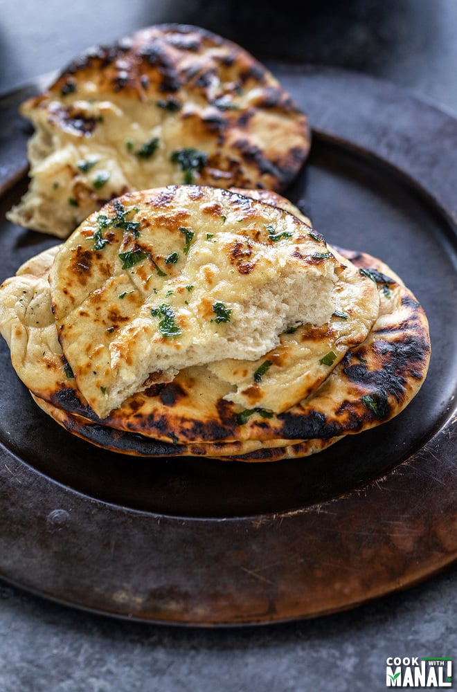 stack of naan with the top naan cut in half to reveal the texture of the bread