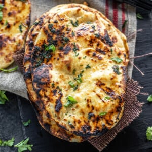 stack of naan garnished with cilantro and placed on a black board