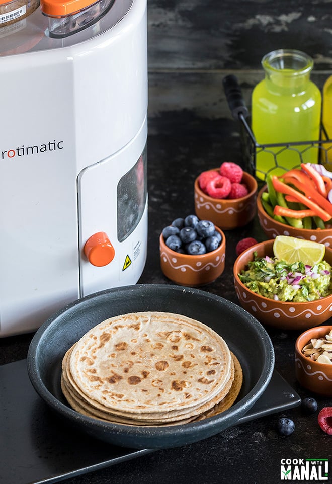 rotis with various toppings in bowls and rotimatic in the background