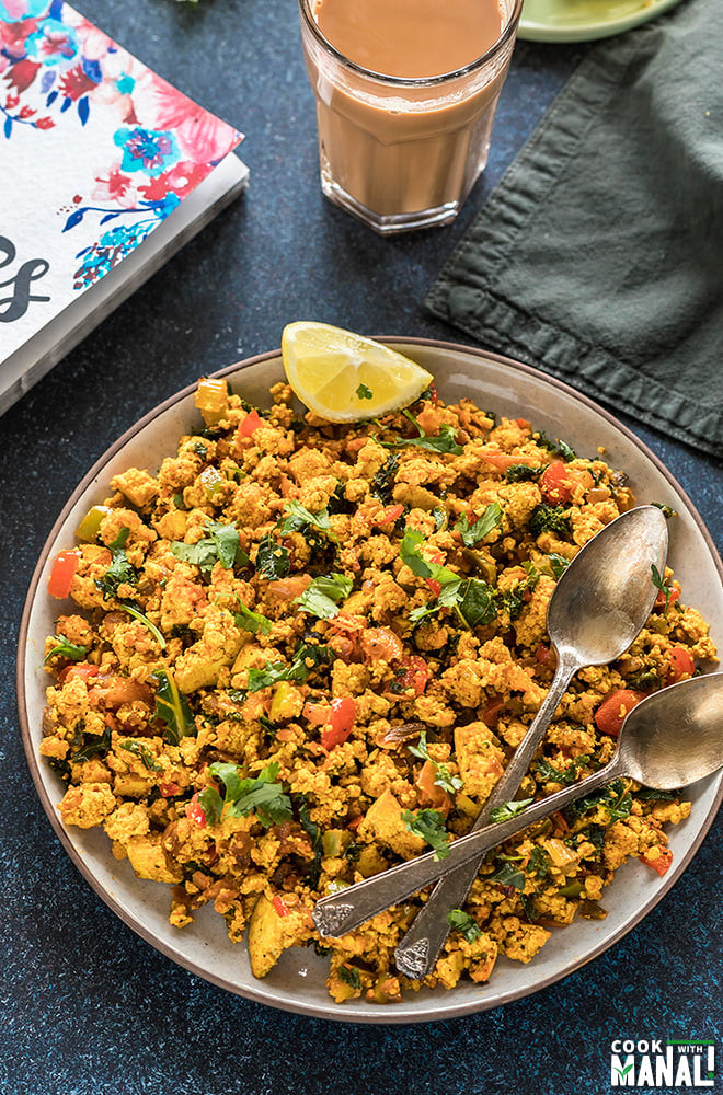 tofu scramble in a round plate with a glass of chai in the background