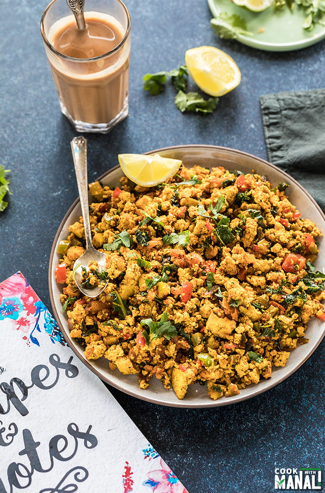 tofu scramble in a round plate with a glass of chai in the background