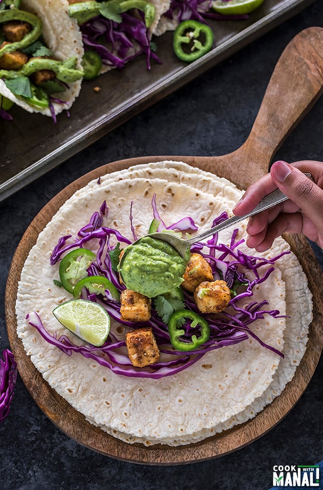 avocado lime crema in a spoon on top of a crispy tofu taco