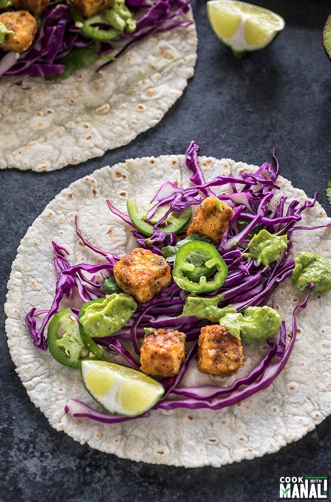 crispy tofu tacos topped with sliced jalapeno and shredded red cabbage