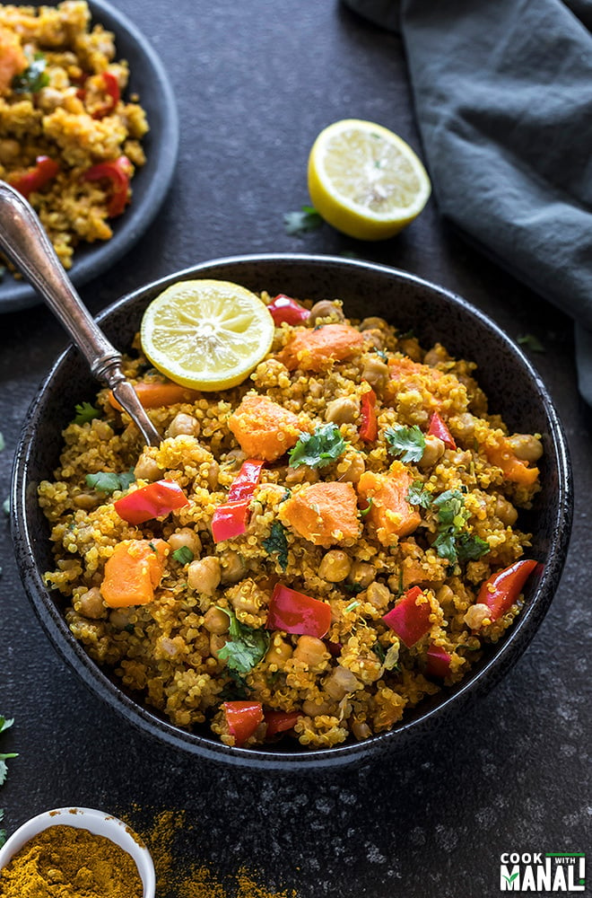 Instant Pot Curried Sweet Potato Chickpea Quinoa in a black bowl and a half cut lemon on the side