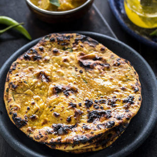 missi roti in black round plate with green chilies in the background