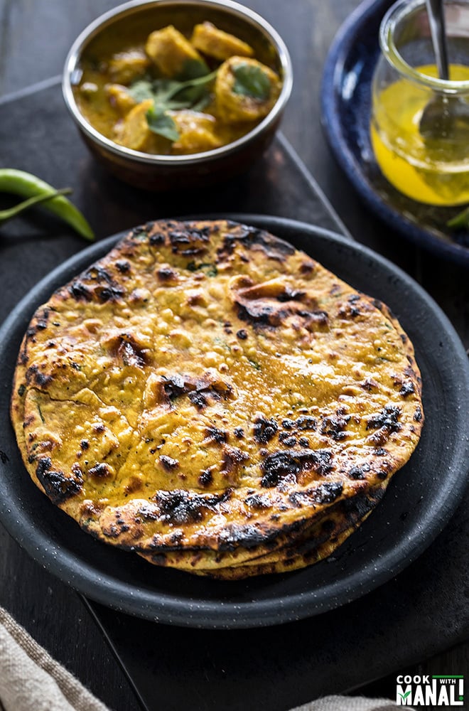 missi roti in black round plate with green chilies in the background
