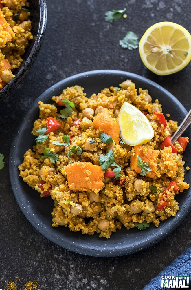 sweet potato chickpea quinoa in a small black plate with a spoon on the side