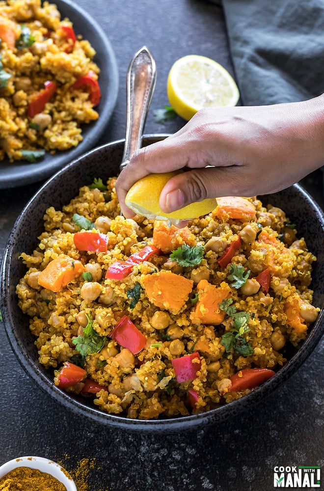 a pair of hands squeezing lemon juice into a bowl of sweet potato chickpea quinoa made in the Instant Pot