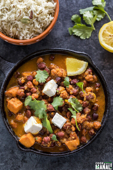 kala chana or black chickpeas curry served in a small cast iron skillet with a lemon and some cilantro on the side