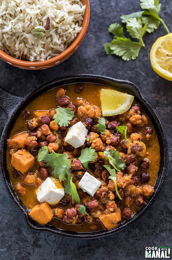 kala chana or black chickpeas curry served in a small cast iron skillet with a lemon and some cilantro on the side